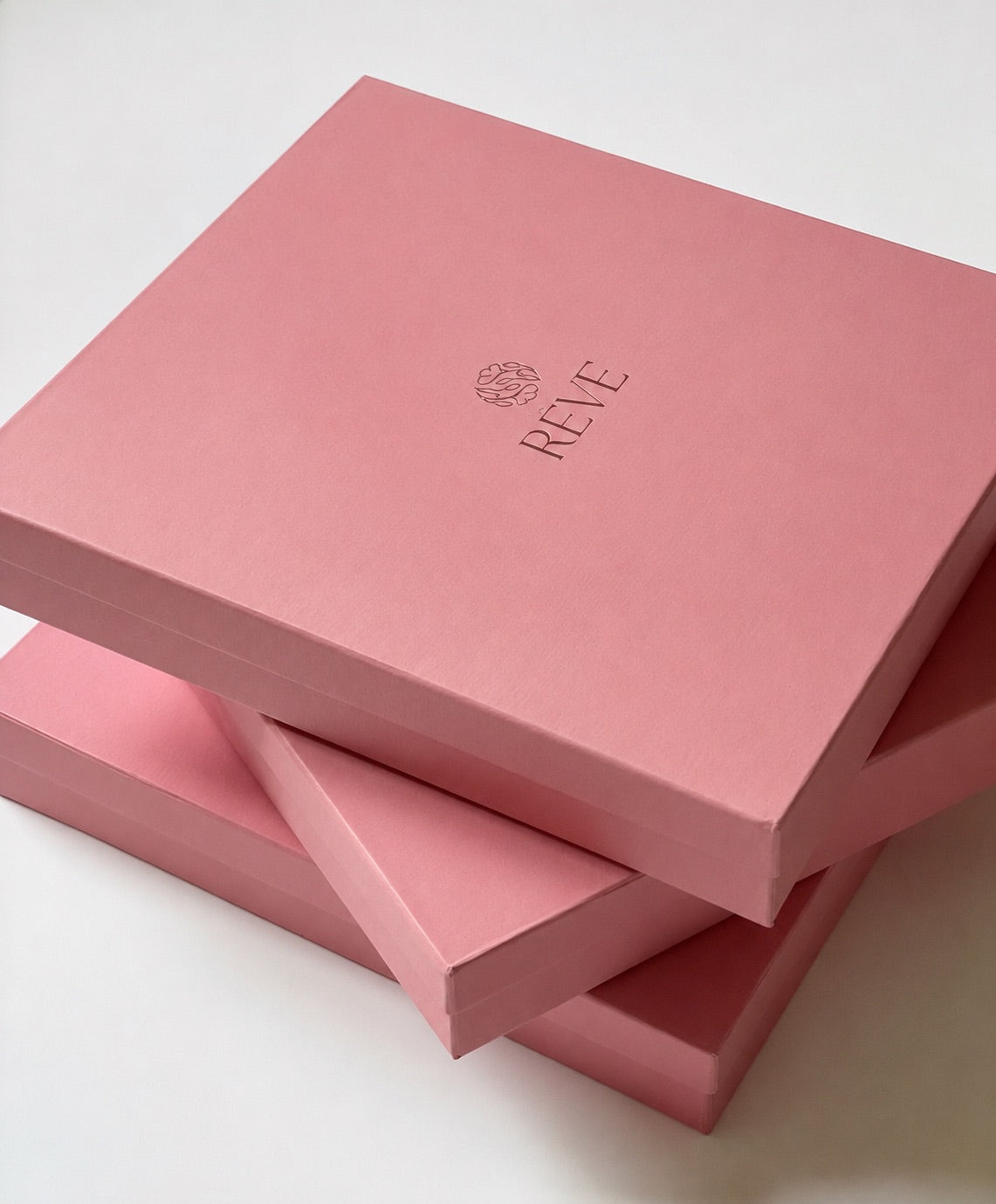 Stacked pink Rêve gift boxes with embossed logo